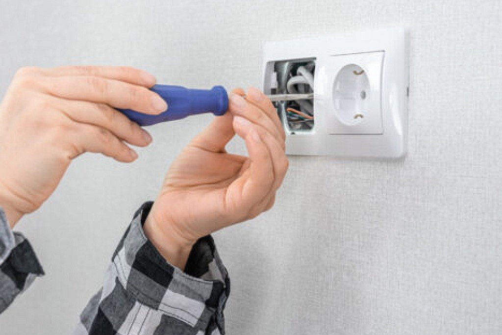 Usługi elektryczne w Legnicy – elektryk przy pracy przy gniazdku